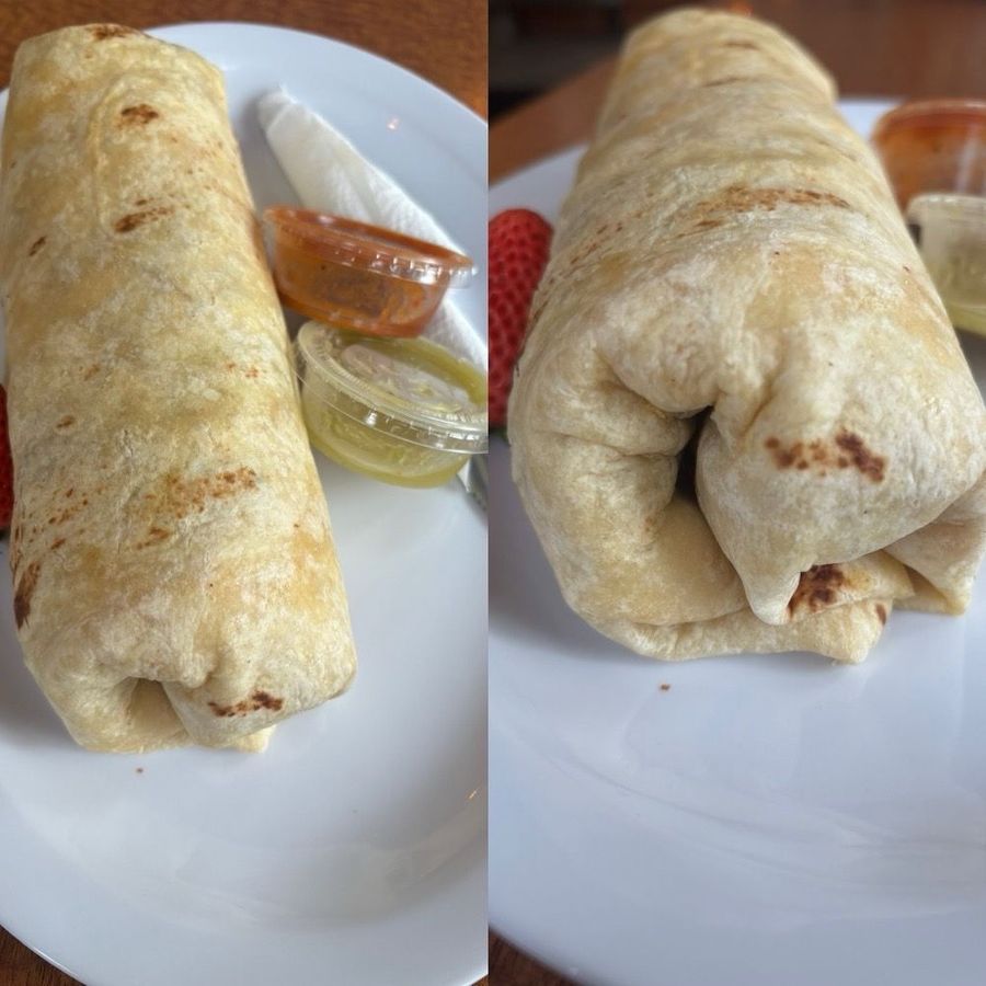 Two burritos wrapped to go on a white plate with salsas