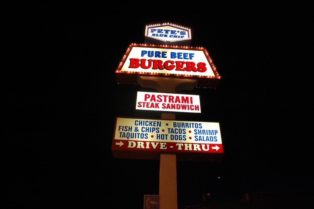 Pete's Blue Chip vintage roadside sign lit up at night: Pure Beef Burgers, Pastrami Steak Sandwich, Drive-Thru