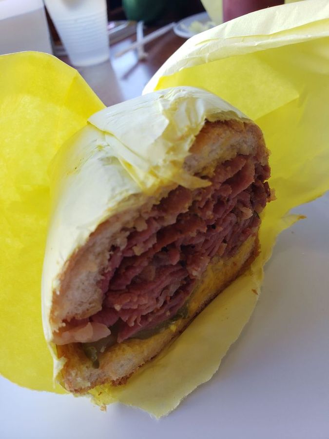 Pastrami sandwich stacked high, wrapped in Pete's yellow paper